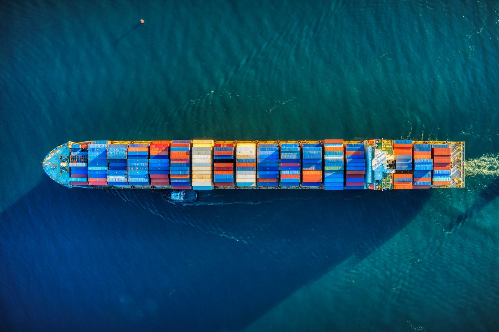 A loaded container ship under way, seen from above on deep teal water